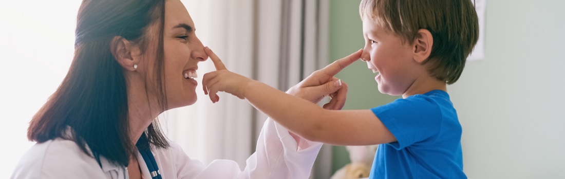 Pediatritian and boy poking noses