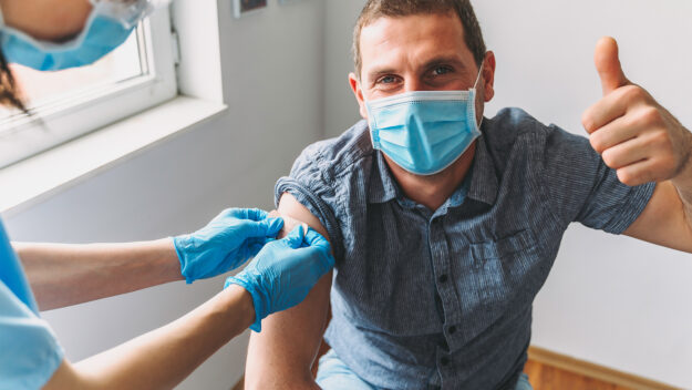 Man with thumb up getting vaccine